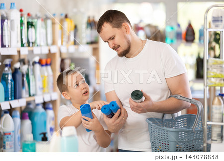Schoolboy son and dad are choosing trash bags in store Schoolboy son and dad are choosing trash bags in store 143078838