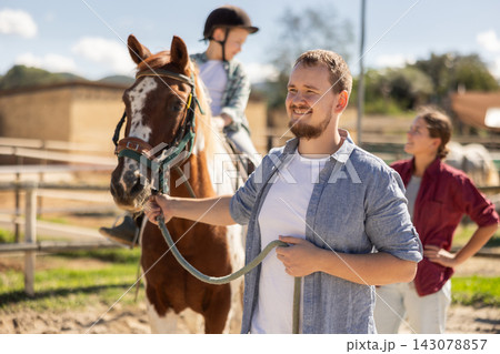 Young man leading horse with boy on horseback Young man leading horse with boy on horseback 143078857
