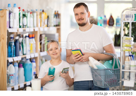 Dad and son filled shopping basket with household purchases, looking for missing items in window 143078903