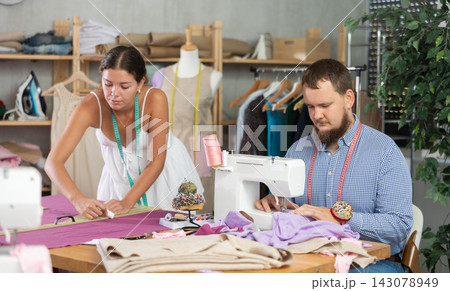 Male dressmaker discussing textile with girl Male dressmaker discussing textile with girl 143078949