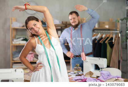 Two young seamstresses doing exercises during break 143079083