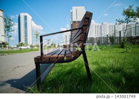 Wooden Park Bench on Green Grass in Urban Courtyard 143081749