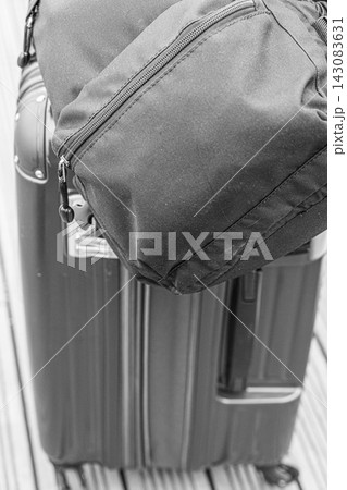 キャリーケースの上に載せたバックパックを写したモノクロの旅行イメージ キャリーケースの上に載せたバックパックを写したモノクロの旅行イメージ 143083631