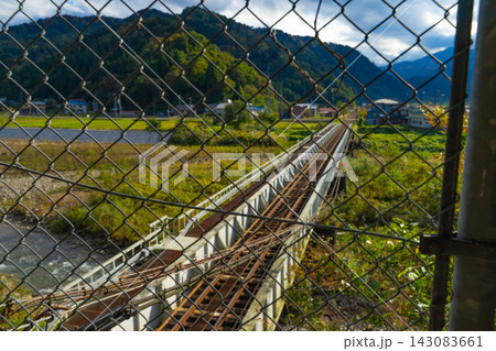 金網越しに望む山あいの鉄道橋と線路 143083661