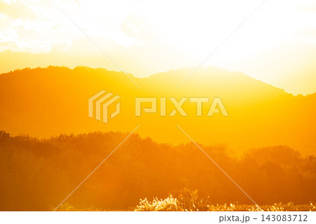 夕日の黄金色の光に包まれる重なる山並み 夕日の黄金色の光に包まれる重なる山並み 143083712