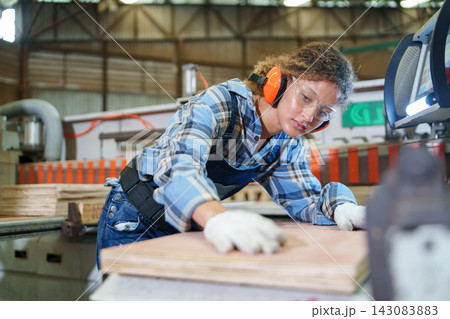 Industrial Worker Operating Machinery in a Woodworking Factory Industrial Worker Operating Machinery in a Woodworking Factory 143083883