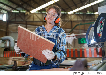 Factory Worker Inspecting Wood Panel on Manufacturing Line Factory Worker Inspecting Wood Panel on Manufacturing Line 143083885