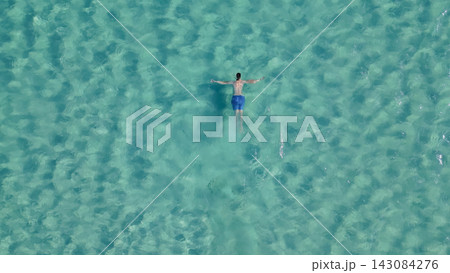 Aerial top down view of man swimming on his back in crystal clear turquoise sea water at Elafonisi beach in paradise island Crete Greece Aerial top down view of man swimming on his back in crystal clear turquoise sea water at Elafonisi beach in paradise island Crete Greece 143084276