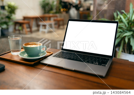 Laptop computer with blank white screen mockup on wooden table in a coffee shop with a cup of latte. Laptop computer with blank white screen mockup on wooden table in a coffee shop with a cup of latte. 143084564