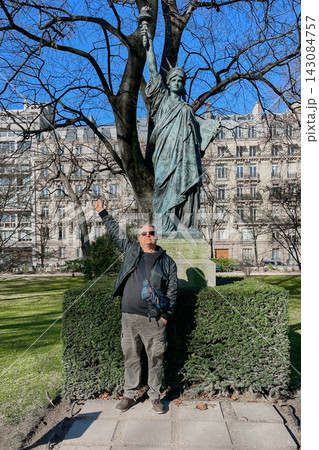 Man posing in front of a Statue of Liberty replica in Paris, France, on a sunny day. Travel, tourism and sightseeing concept. High quality photo Man posing in front of a Statue of Liberty replica in Paris, France, on a sunny day. Travel, tourism and sightseeing concept. High quality photo 143084757