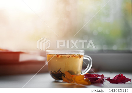 Cozy autumn still life with hot tea, books and fall leaves by rainy window Cozy autumn still life with hot tea, books and fall leaves by rainy window 143085113