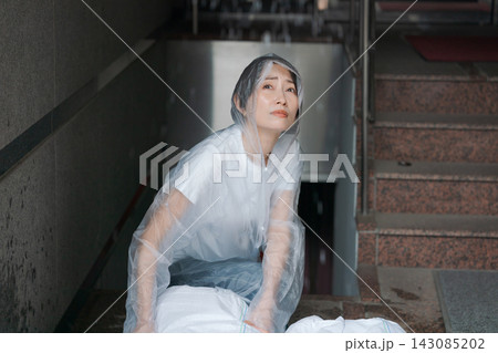 土のう袋を積んで水害対策をする女性 143085202