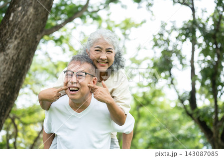 Elderly Asian Couple Piggyback Ride With Playful Face Pinching And Big Smiles. 143087085