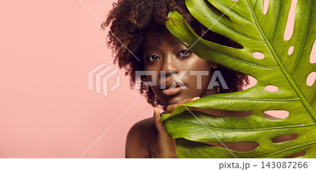Portrait of african american nude woman looking out of tropical leaf. Portrait of african american nude woman looking out of tropical leaf. 143087266