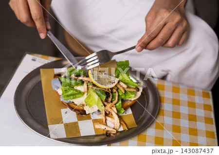 Top view of a woman using knife and fork to enjoy mushroom and ricotta open toast. 143087437