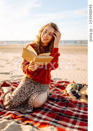 Woman reading book while lying on blanket during picnic. Concept of relaxation, solitude with nature Woman reading book while lying on blanket during picnic. Concept of relaxation, solitude with nature 143088048