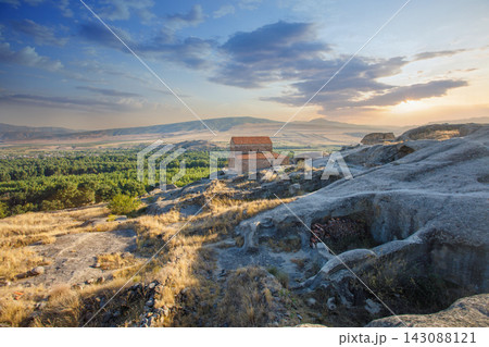 Georgian landscape with orthodox church, ancient cave town and sunset sky in Uplistikhe, Georgia Georgian landscape with orthodox church, ancient cave town and sunset sky in Uplistikhe, Georgia 143088121