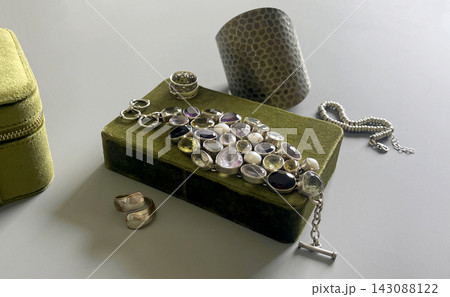 Collection of silver jewelry displayed on a green box in a bright room during the day Collection of silver jewelry displayed on a green box in a bright room during the day 143088122