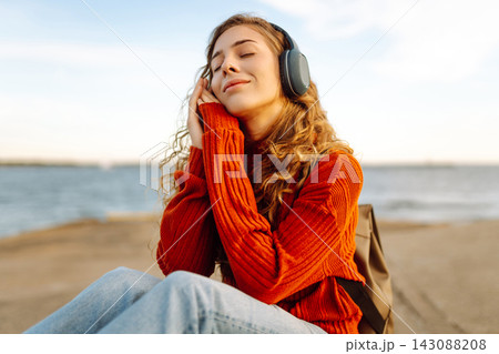 Portrait of beautiful young girl enjoying freedom listening to music against the backdrop of the sea Portrait of beautiful young girl enjoying freedom listening to music against the backdrop of the sea 143088208