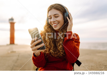 Portrait of beautiful young girl enjoying freedom listening to music against the backdrop of the sea Portrait of beautiful young girl enjoying freedom listening to music against the backdrop of the sea 143088216