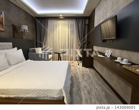 Modern hotel bedroom with neatly made bed, television, desk, armchair, curtains, and elegant interior Modern hotel bedroom with neatly made bed, television, desk, armchair, curtains, and elegant interior 143089085