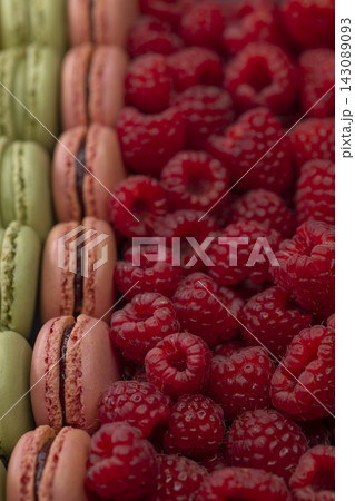 macaroons of different colors with raspberries 143089093