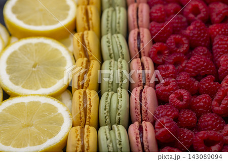macaroons of different colors with raspberries and lemon 143089094