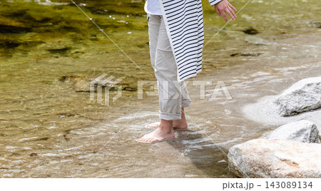 川の浅瀬を歩く女性の足元、水しぶきが舞う 143089134