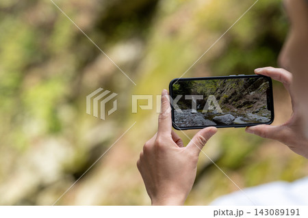 スマホで川辺の風景を撮影する手元 143089191