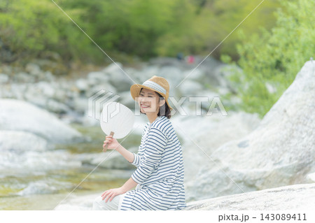 川辺でうちわを持つ笑顔の女性 川辺でうちわを持つ笑顔の女性 143089411