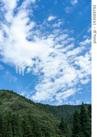 森林の山並みと白い雲の広がる青空の縦構図 森林の山並みと白い雲の広がる青空の縦構図 143089792