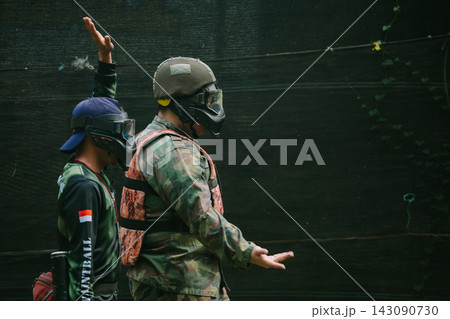 Paintball Players Communicating Tactics Outdoors in Protective Gear Paintball Players Communicating Tactics Outdoors in Protective Gear 143090730