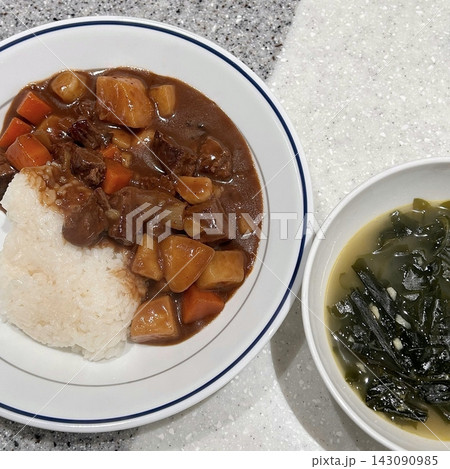 A comforting bowl of Japanese curry, featuring a rich, savory sauce with tender vegetables and chunks of meat, served over fluffy rice. A warm, flavorful dish perfect for any meal. 143090985