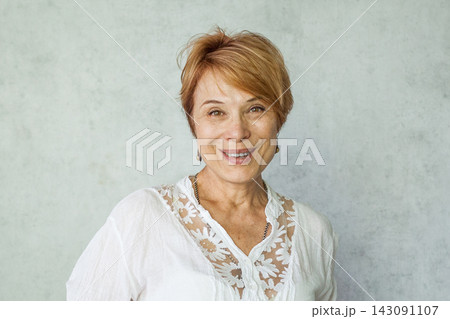 Joyful elegant senior woman wearing casual white shirt standing over grey background 143091107