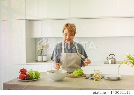 Pretty senior woman chopping and cutting vegetable, making breakfast. Preparation, cookery Pretty senior woman chopping and cutting vegetable, making breakfast. Preparation, cookery 143091113
