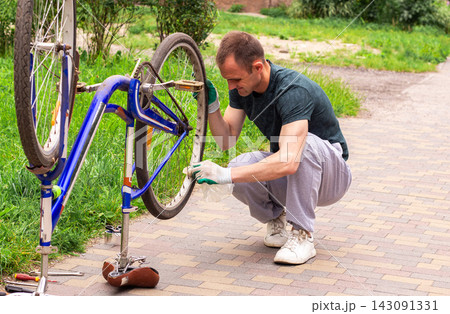 Man washing bike after keeping it in basement during cold days. Keeping transport clean and functional. Hands on approach to property care. Seasonal bicycle preparation for summer 143091331