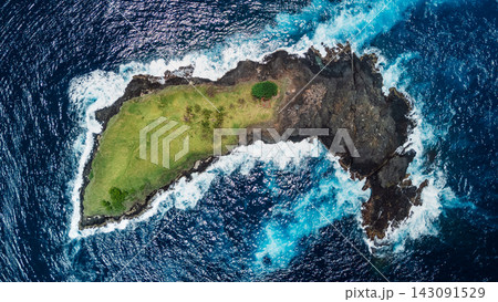Above view of a small green rocky island surrounded by deep blue ocean 143091529