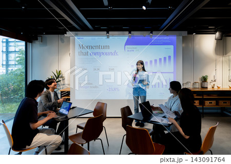 売上成長データを背景にビジネスチームへプレゼンする女性 143091764