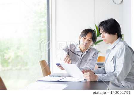 資料を確認しながら打ち合わせをする日本人の男性作業員 143091791