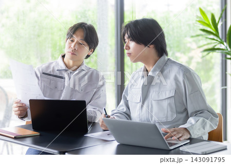 ノートパソコンと資料を確認しながら打ち合わせをする日本人の男性作業員 ノートパソコンと資料を確認しながら打ち合わせをする日本人の男性作業員 143091795