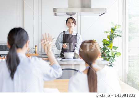 料理教室で女性講師に質問する日本人女性の生徒 料理教室で女性講師に質問する日本人女性の生徒 143091832