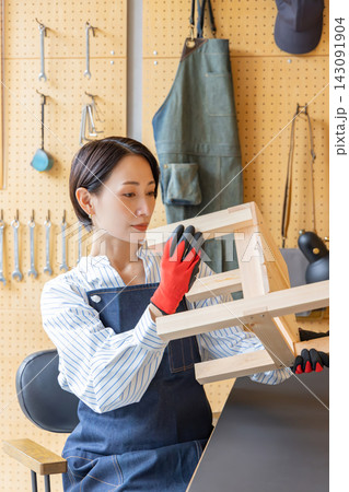 DIY工房で完成した木製椅子を確認する日本人女性 DIY工房で完成した木製椅子を確認する日本人女性 143091904