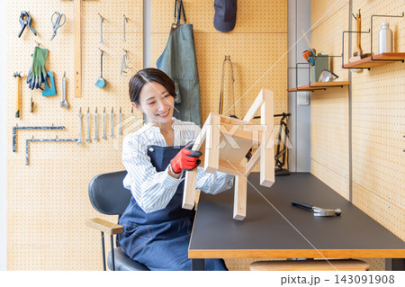 DIY工房で完成した木製椅子を確認する日本人女性 143091908