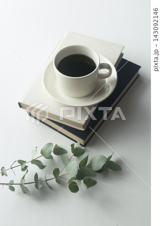 本とコーヒーカップ、ユーカリを添えたナチュラルな暮らしのイメージ 143092146