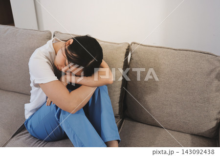 Young woman suffering from depression feeling sad and lonely on sofa at home Young woman suffering from depression feeling sad and lonely on sofa at home 143092438