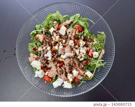 Fresh Mediterranean salad with arugula tuna cherry tomatoes feta cheese and balsamic glaze in glass bowl. Healthy nutrition and organic gourmet dining concept Fresh Mediterranean salad with arugula tuna cherry tomatoes feta cheese and balsamic glaze in glass bowl. Healthy nutrition and organic gourmet dining concept 143093715