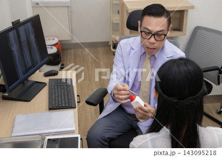 male doctor in a white coat explaining medication and prescription details to a female patient  143095218