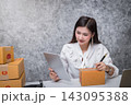 Successful entrepreneur business woman checking order via tablet with online sales and parcel shipping in her home office. 143095388