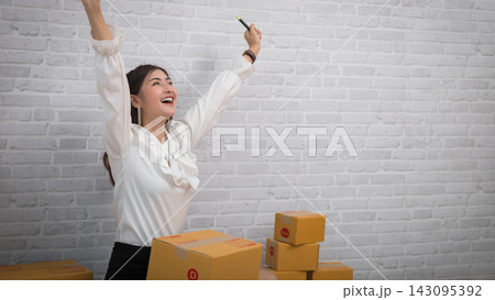 Happy Asian Business Woman Successful Excited Raised Hands Rejoicing. Asian small business owner is successful selling online using laptop computer. selling online, pacel box. Happy Asian Business Woman Successful Excited Raised Hands Rejoicing. Asian small business owner is successful selling online using laptop computer. selling online, pacel box. 143095392