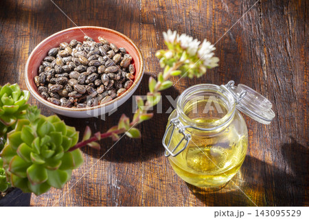 Castor grains and oil on the table, close-up image Castor grains and oil on the table, close-up image 143095529